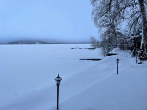 Deux lumières dans la neige à côté d'un lac dans l'établissement Villa Joutsen, à Hollola