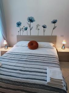 a bed with a blue and white striped comforter with a orange pillow at F.A.M. ROOMS in Ciampino