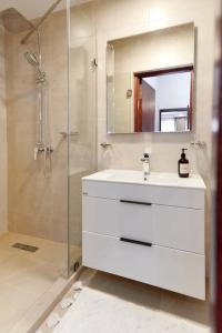 a bathroom with a sink and a shower with a mirror at Stylish 2 Bedroom in Osu in Accra