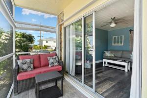 eine überdachte Veranda mit einem roten Sessel und einem Sofa in der Unterkunft Seashells Getaway - Boat Slip, Ramp, Pool in Marathon