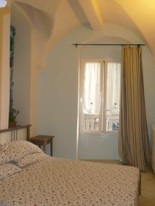 a bedroom with a bed and a window with curtains at Casa Della Lavanda in Santo Stefano al Mare