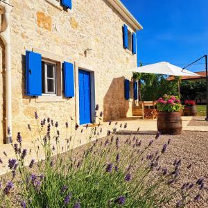 een stenen huis met blauwe luiken en paarse bloemen bij Villa Laura - Home Away From Home in Labin