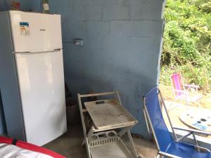 uma cozinha com um frigorífico, uma mesa e cadeiras em Camping Toninhas em Ubatuba