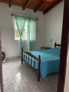 a bedroom with a bed with a blue comforter and a window at PULAKI Cabañas en Animana in Animaná