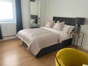 a bedroom with a large bed and a yellow chair at Anfield Home Sleeps 5 Close to LFC free parking in Liverpool