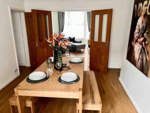 a living room with a wooden table with plates and flowers at Anfield Home Sleeps 5 Close to LFC free parking in Liverpool