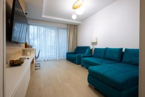 uma sala de estar com um sofá azul e uma televisão em Premier Luxury Apartment Lake On em Mamaia