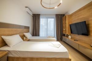 a hotel room with two beds and a flat screen tv at Premier Luxury Apartment Lake On in Mamaia
