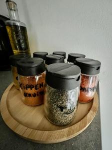 a group of four jars of spices on a wooden plate at Isa's Appartement in Lommel