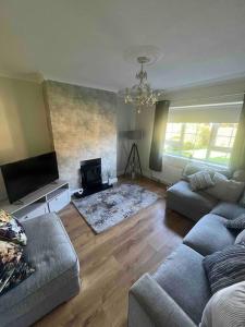 a living room with two couches and a fireplace at Cosy 4 bed bungalow in quiet residential area! in Strabane