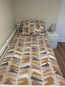 a bed with a colorful comforter in a bedroom at Cosy 4 bed bungalow in quiet residential area! in Strabane