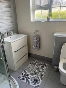 y baño con lavamanos, aseo y alfombra. en Cosy 4 bed bungalow in quiet residential area!, en Strabane