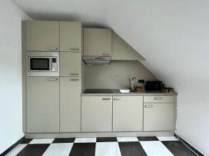 a kitchen with white cabinets and a microwave at Isa's Appartement in Lommel