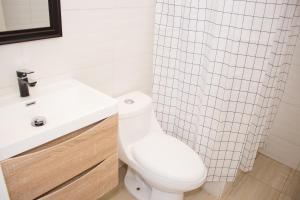 La salle de bains est pourvue de toilettes, d'un lavabo et d'un rideau de douche. dans l'établissement Casa Baron, à Valparaíso