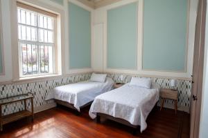 2 camas en una habitación con 2 ventanas en Casa Baron en Valparaíso