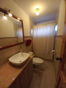 ein Badezimmer mit einem Waschbecken, einem WC und einem Spiegel in der Unterkunft La Loma in Cajamarca