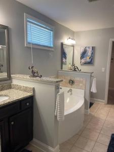 a bathroom with a tub and a sink and a mirror at Spacious Home Near Shaw in Sumter