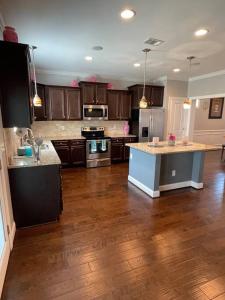 a large kitchen with wooden floors and stainless steel appliances at Spacious Home Near Shaw in Sumter