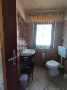 baño con lavabo y aseo y ventana en Casa di Viu', en Viù