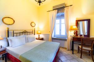 a bedroom with a bed and a desk and a window at Archontiko Eleni Hotel in Andros