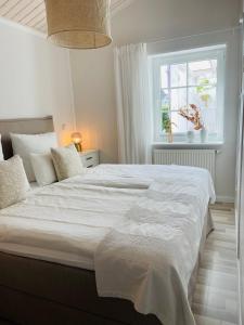 a bedroom with a large white bed with a window at Strandzone 29 in Kronsgaard