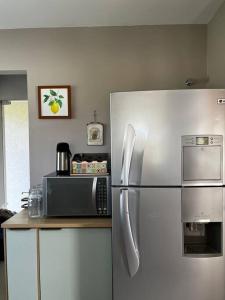 eine Küche mit einem Kühlschrank aus Edelstahl und einer Mikrowelle in der Unterkunft Linda Casa Sonnenhaus Witmarsum in São Luís do Purunã