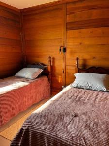 2 Betten in einem Zimmer mit Holzwänden in der Unterkunft Linda Casa Sonnenhaus Witmarsum in São Luís do Purunã