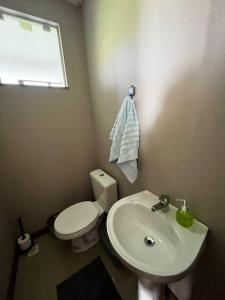La salle de bains est pourvue de toilettes blanches et d'un lavabo. dans l'établissement Linda Casa Sonnenhaus Witmarsum, à São Luís do Purunã