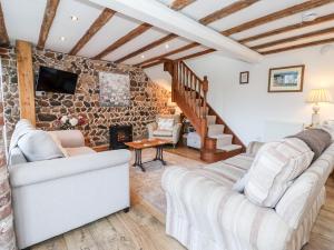sala de estar con sofá y pared de piedra en The Cart House en Barmston