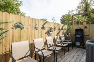 einen Holzzaun mit Stühlen und einen TV auf einer Terrasse in der Unterkunft Luxury Beach Retreat Townhouse Sleeps 8 in Gulfport