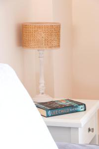 a bedside table with a lamp and a book at Louiza Apartments in Agios Gordios