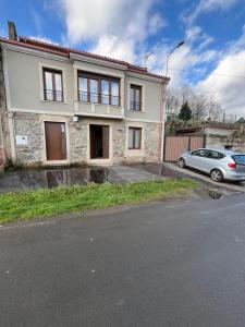 una casa con una macchina parcheggiata di fronte di Casa Victoriano a Melide