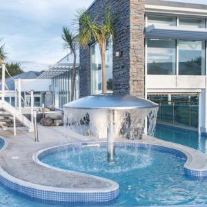 a swimming pool with a fountain in front of a building at Weymouth Bay Haven, Preston Road in Weymouth