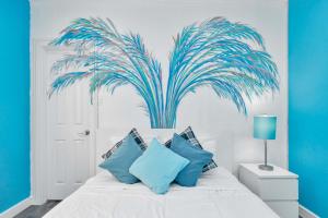 um quarto com uma cama branca e almofadas azuis em Prolific Blue Oasis near Med Ctr Dwntwn Galleria em Houston