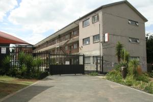 a building with a fence next to a driveway at Libem Lodge 11 in Edenvale