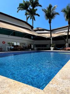 a swimming pool in front of a building with palm trees at Bene Beach - Pousada Guarujá in Guarujá