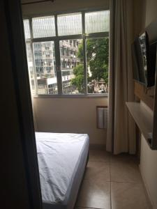 um quarto com uma cama em frente a uma janela em Loft Aconchegante no Centro de Niterói!! em Niterói