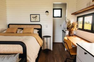 a bedroom in a tiny house with a bed and a desk at Tiny House Purunã - Refúgio Inspirador in Balsa Nova