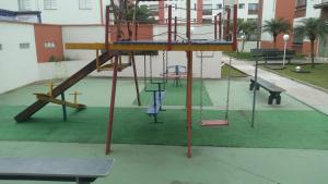 um parque infantil com escorrega e um baloiço em Apartamento em Itanhaém com 2 quartos, Piscina e Ampla Varanda Gourmet em Itanhaém