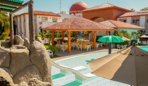 a pool with an umbrella and tables and chairs at María Isabel Colima in Colima