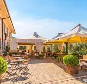 patio ze stołami, krzesłami i parasolami w obiekcie Agriturismo Poggio Tondo w mieście Monsummano Terme