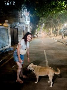 uma mulher ao lado de um cão numa rua em Santa Maria Hostel, Fort Kochi em Cochin
