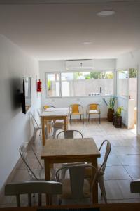 a dining room with tables and chairs and a kitchen at Casa Amonite Hostel Boutique in Puerto Madryn