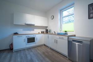 eine Küche mit weißen Schränken und einem Fenster in der Unterkunft Stellmann’s Gästehof in Bruchhausen-Vilsen