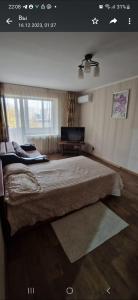 1 dormitorio con 1 cama grande y TV en Однокомнатная квартира в Караганде, en Karagandá