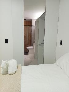 a bedroom with a white bed and a bathroom at perla del norte in Bello