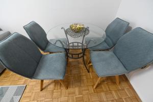 a glass table with four blue chairs around it at Apartman N&D in Banja Luka