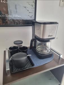 une cafetière assise sur une étagère avec des tasses dans l'établissement Flat Beira Mar Terrazzas, à João Pessoa