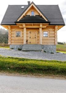 a log cabin with a black roof and a door at Chałpy Pod Ostryszem in Ciche