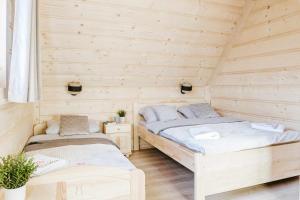 two beds in a room with wooden walls at Chałpy Pod Ostryszem in Ciche